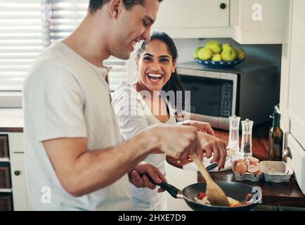 Wir lieben es, gemeinsam Mahlzeiten zuzubereiten. Eine kleine Aufnahme eines glücklichen jungen Paares, das zusammen das Frühstück vorbereitet. Stockfoto