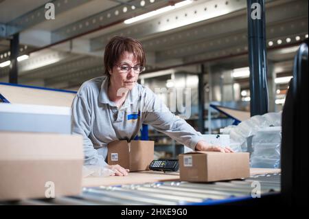 Frau, die die Bestellung eines Kunden in einem Lager verpackt Stockfoto