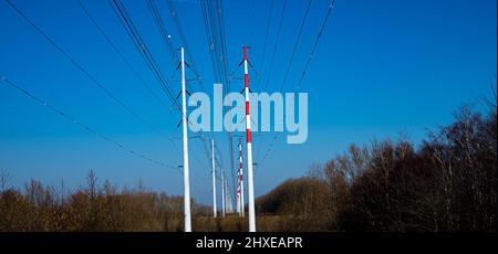 Hochspannungsleitungen, die an Leitungstürmen in einer wunderschönen Naturlandschaft mit natürlichem blauen Himmel angeschlossen sind Stockfoto