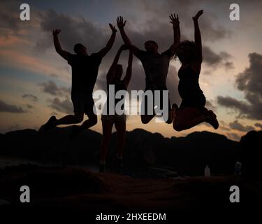 Springen vor Freude. Aufnahme einer Gruppe von springenden Freunden, die gegen einen Sonnenuntergang gedreht wurden. Stockfoto