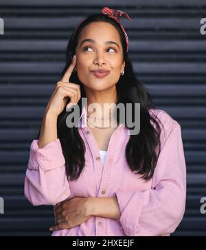 Shes ein Denker. Beschnittene Aufnahme einer attraktiven jungen Frau, die nachdenklich aussieht, während sie vor einem grauen Hintergrund posiert. Stockfoto