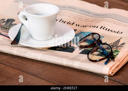 Zeitungen und eine Tasse Kaffee mit Schlagzeile KRIEG GEGEN RUSSLAND auf dem Tisch drinnen Stockfoto