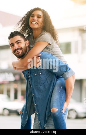 Wenn du tief verliebt bist, kann alles Spaß machen. Aufnahme eines verspielten Paares, das gemeinsam in der Stadt unterwegs ist. Stockfoto