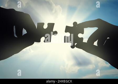 Die Teile zusammenfügen. Kurzer Schuss Hände mit zwei Puzzleteilen. Stockfoto