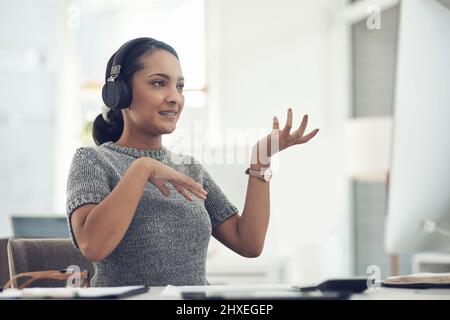 Ihre großen Ideen während eines virtuellen Meetings präsentieren. Aufnahme einer jungen Geschäftsfrau mit Kopfhörern während eines Videoanrufs auf einem Computer in einem Büro. Stockfoto