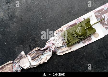 Wirtschaftskrise in Russland Konzept. Spielzeug militärischen Panzer auf russischen Rubel. Kriegskonflikt in der Ukraine, Wirtschaftssanktionen und Inflation in Russland. Hochwertige Fotos Stockfoto