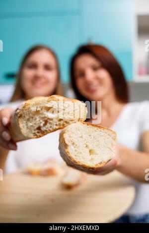 Baker's Hände brechen heißes frisches Weizenbrot in zwei Hälften, Crunch und Krümel. Selektiver Fokus Stockfoto