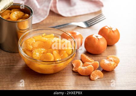 Mandarine aus der Dose. Eingelegte Mandarinenfrüchte in der Schüssel auf einem Holztisch. Stockfoto