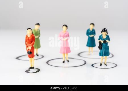 Einzelne Miniatur-weibliche Modelle isoliert in Kreisen auf einer weißen Oberfläche gezeichnet Stockfoto