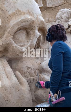 Binz, Deutschland. 11. März 2022. Eine Frau arbeitet an einer Sandskulptur der Sandskulptur-Show 'What a wonderful world'. Die Skulpturen zeigen Landschaften, Menschen und Fabelwesen. Quelle: Stefan Sauer/dpa/Alamy Live News Stockfoto