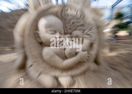 Binz, Deutschland. 11. März 2022. Die Sandskulptur eines Babys der Sandskulptur zeigt 'What a wonderful world' (Aufnahme mit Zoom-Effekt). Die Skulpturen zeigen Landschaften, Menschen und Fabelwesen. Quelle: Stefan Sauer/dpa/Alamy Live News Stockfoto