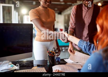 Eine junge Frau stellt sich ihrer neuen Kollegin in einer freundlichen Atmosphäre im Büro vor Stockfoto