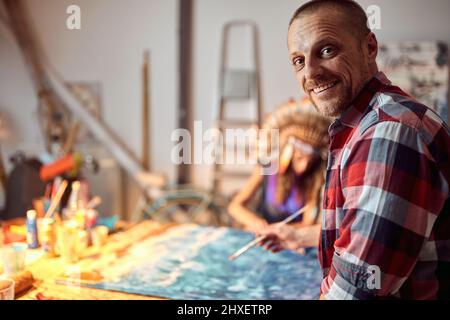 Nahaufnahme eines jungen männlichen Künstlers, während er in angenehmer Atmosphäre im Studio für ein Foto posiert. Kunst, Malerei, Atelier Stockfoto