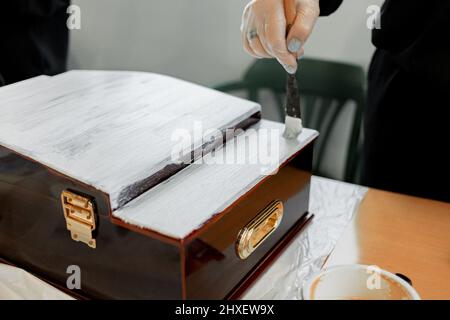 Meisterkurs zum Bemalen von Möbeln, Damenhänden arbeiten mit dem Grundierpinsel Stockfoto