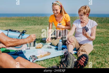 Junge Frau und ältere Frau spielen während eines Ausflugs in der Familie Karten Stockfoto