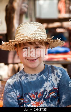 Junge ist entspannend, lächelnd und glücklich und hat eine Pause in der Sonne an einem Open air Restaurant Stockfoto