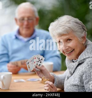 Mit Kartenspielen die Zeit verstreichen lassen. Zwei Senioren spielen zusammen Karten. Stockfoto