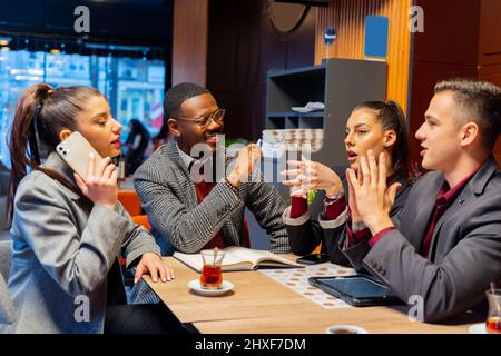 Eine Gruppe von multirassischen Geschäftsleuten führt ein ernsthaftes Gespräch und lächelt Stockfoto