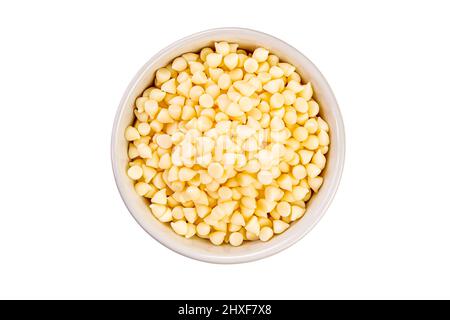 Draufsicht auf weiße Schokoladensplitter in Keramikbecher auf weißem Hintergrund mit Schneideweg. Stockfoto