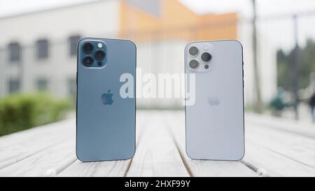 Moskau - Russland, 10.10.2021: Präsentation des neuen iPhone 13 Pro Max. Aktion. Konzept der neuen Technologien, zwei Smartphones stehen auf einer Bank im Freien. Stockfoto