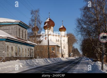 Russische nördliche Provinzstadt Kargopol. Kirche der Verkündigung der Seligen Jungfrau neben verlassenen hölzernen Wohngebäuden. Stockfoto