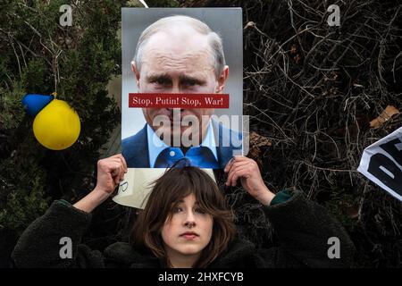 Madrid, Spanien. 12. März 2022. Während eines Protestes gegen den Krieg wird eine junge Frau mit einem Plakat mit dem Bild des russischen Präsidenten Wladimir Putin gesehen. In Madrid lebende Ukrainer und Russen versammelten sich, um vor der russischen Botschaft gegen die russische Invasion in der Ukraine zu protestieren und das Ende des Krieges zu fordern. Quelle: Marcos del Mazo/Alamy Live News Stockfoto