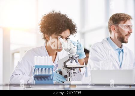Wissenschaftlerin, die durch ein Mikroskop schaut. Nahaufnahme. Stockfoto
