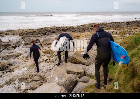 Surfer kommen in der Rest Bay in Porthcawl ins Meer, da über das Wochenende eine gelbe Windwarnung in West Wales in Kraft ist. Bilddatum: Samstag, 12. März 2022. Stockfoto