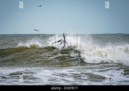 Surfer reiten in Rest Bay in Porthcawl auf den Wellen, während über das Wochenende eine gelbe Windwarnung in West Wales in Kraft ist. Bilddatum: Samstag, 12. März 2022. Stockfoto