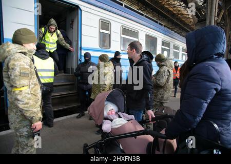 LVIV, UKRAINE - 11. MÄRZ 2022 - Eine Frau mit einem Baby im Kinderwagen steht auf der Plattform, während Menschen, die vor der russischen Invasion fliehen, auf einen Evakuierungszug warten Stockfoto