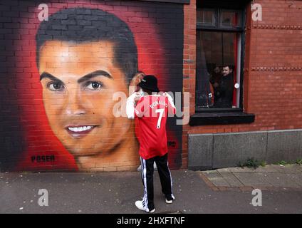 Manchester, England, 12.. März 2022. Ein Manchester United-Fan posiert neben einem Wandgemälde von Cristiano Ronaldo vor dem Premier League-Spiel in Old Trafford, Manchester. Bildnachweis sollte lauten: Darren Staples / Sportimage Credit: Sportimage/Alamy Live News Stockfoto