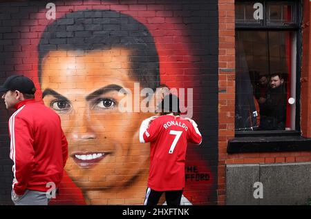 Manchester, England, 12.. März 2022. Ein Manchester United-Fan posiert neben einem Wandgemälde von Cristiano Ronaldo vor dem Premier League-Spiel in Old Trafford, Manchester. Bildnachweis sollte lauten: Darren Staples / Sportimage Credit: Sportimage/Alamy Live News Stockfoto