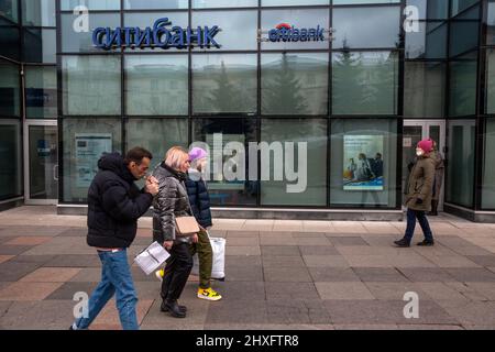 Moskau, Russland. Am 12.. März gehen 2022 Menschen auf einer Straße im Hintergrund des Büros der Citi Bank in Leningradskoe Shosse in Moskau, Russland Stockfoto