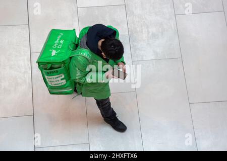 Moskau, Russland. 12.. März 2022 Luftaufnahme eines Kuriers des 'Delivery Club'-Lebensmittellieferdienstes in einem Einkaufszentrum in Moskau, Russland Stockfoto