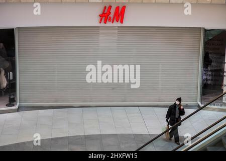 Moskau, Russland. 12.. März 2022 Kunde bleibt in der Nähe eines geschlossenen H&M-Stores im Metropolis-Einkaufszentrum. Am 2. März 2022 hat der schwedische Modehändler H&M vorübergehend alle Verkäufe in Russland eingestellt Stockfoto