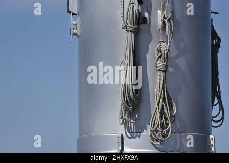 Luxus-Segelyacht-Riemenscheiben und Verankerungsseile auf dem Boden eines Edelstahlmastes. Stockfoto