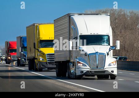 Horizontale Aufnahme eines farbigen Konvois schwerer Sattelschlepper auf der Autobahn. Stockfoto