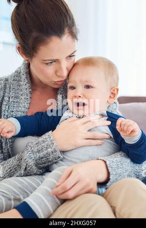 Weint nicht, mein Engel, Mama ist hier. Eine kurze Aufnahme einer Mutter, die zu Hause versucht, ihren weinenden Jungen zu trösten. Stockfoto