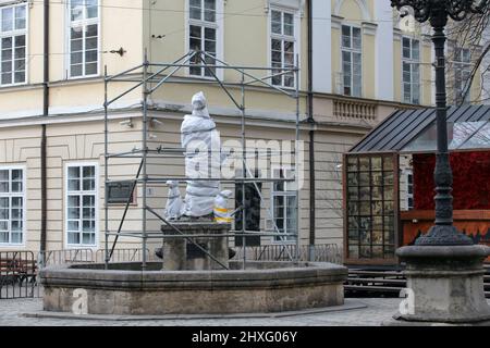 LVIV, UKRAINE - 10. MÄRZ 2022 - der Diana-Brunnen auf dem Rynok-Platz wurde versiegelt, um ihn vor Beschädigungen im Falle eines möglichen russischen A zu schützen Stockfoto