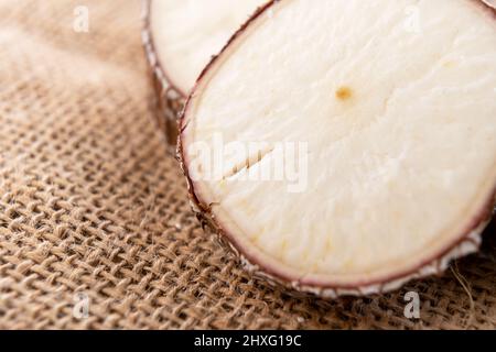 Geschnittene Maniok-Yucca-Wurzel auf rustikalem Sackleinen-Tuch. Makro Stockfoto