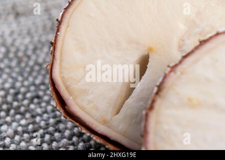 Cassava-Yucca-Wurzel mit Riss aus nächster Nähe auf rustikaler rauer Jute. Makro. In Scheiben geschnittenes, rohes Maniok Stockfoto