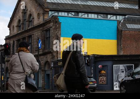 Glasgow, Großbritannien, 12.. März 2022. Die ukrainische Flagge wurde an einer Wand über der Clutha & Victoria Bar angebracht, was die Unterstützung der Ukraine in ihrem aktuellen Krieg mit Präsident PutinÕs Russland in Glasgow, Schottland, am 12. März 2022, zeigt. Foto: Jeremy Sutton-Hibbert/ Alamy Live News. Stockfoto