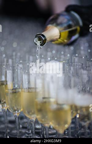 Champagner, der Gläser aus einer Flasche eingießt. Spritzer und Tropfen. Konzept für den Urlaub. Stockfoto