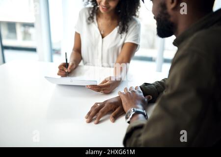 Die Knicke des Vertrags ausbügeln. Aufnahme eines jungen Geschäftsmannes und einer Geschäftsfrau, die während eines Meetings in einem modernen Büro Schreibarbeit ausfüllte. Stockfoto