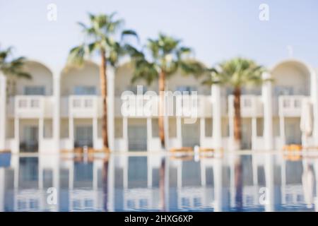 Leere Liege mit Sonnenschirm um den Pool. Wunderschöner Swimmingpool im tropischen Resort. Stockfoto