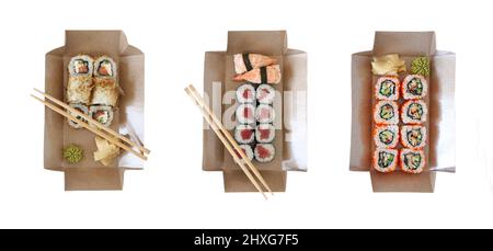 Leckere Sushi-Rollen mit Saucen und Essstäbchen in Einweg-Kraftpapier-Boxen isoliert auf weißem Hintergrund. Japanisches Konzept für den Lieferservice von Lebensmitteln Stockfoto