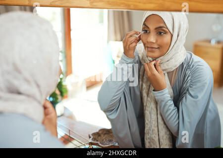 Bereit für die Straße. Aufnahme einer jungen muslimischen Frau, die zu Hause den Spiegel benutzte. Stockfoto