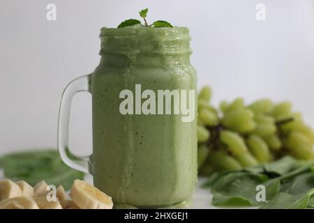 Grüner Smoothie aus gefrorenen grünen Trauben, frischem Babyspinat, Bananen und Mandelmilch. Serviert im Einmachglas. Aufgenommen auf weißem Hintergrund. Stockfoto