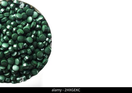 Grüne Tabletten aus natürlichem Spirulina aus kontrolliert biologischem Anbau in einer Tasse auf weißem Hintergrund mit freiem Raum Draufsicht Stockfoto