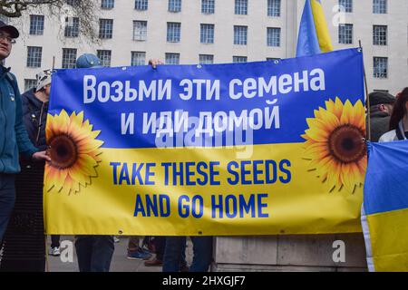 London, Großbritannien. 12.. März 2022. Die Demonstranten halten ein Transparent mit Sonnenblumen mit der Aufschrift „Nimm diese Samen und geh nach Hause“. Demonstranten versammelten sich vor der Downing Street zur Unterstützung der Ukraine, während Russland seinen Angriff fortsetzt. Kredit: Vuk Valcic/Alamy Live Nachrichten Stockfoto